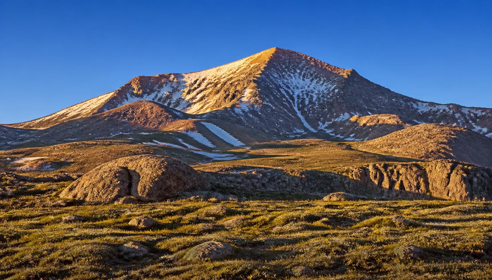 The snow-streaked summit of Pikes Peak above treeline in early morning light